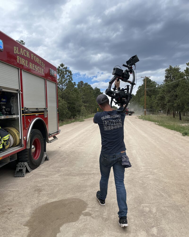 Camera operator with a gimbal rig filming beside a fire truck, behind the scenes of Mind Shift fire service video production
