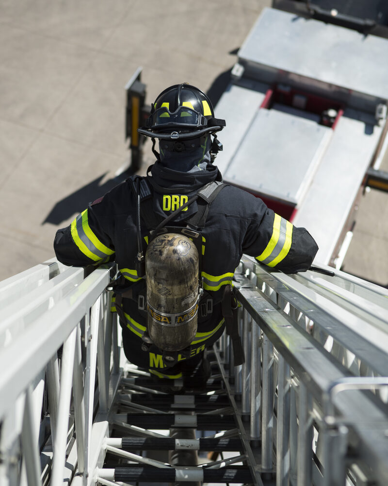 Firefighter climbing an aerial ladder at a working fire, firefighter photography by Mind Shift