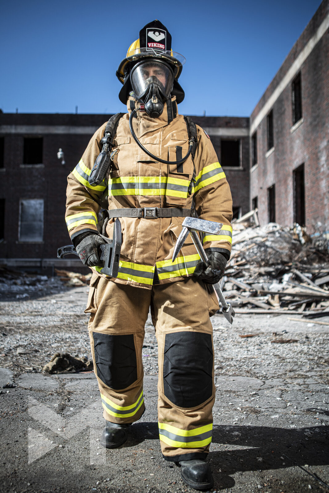 Firefighter in turnout gear staging with tools at a derelict brick training building, fire service photography by Mind Shift