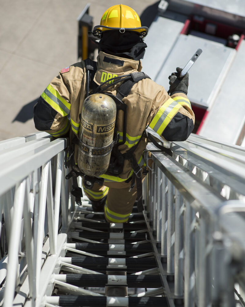 Firefighter in full SCBA climbing an aerial ladder, fire service photography by Mind Shift